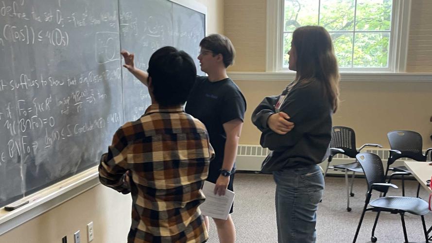 three math students work on a chalkboard