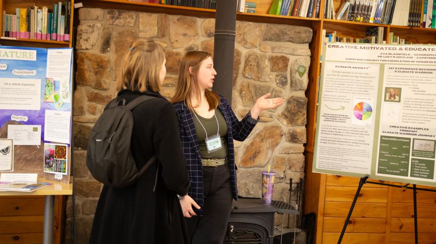 A coed explains her poster and research to a participant at the sustainability expo held at  Shaver's Creek Environmental Center.