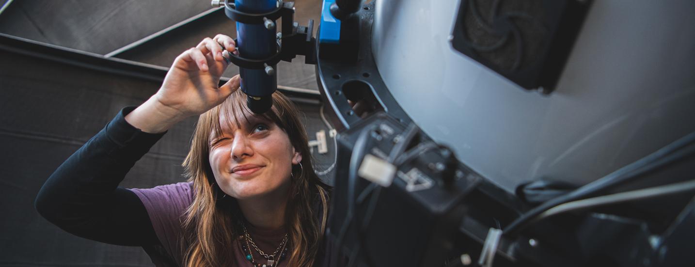 A graduate student from the Department of Astronomy and Astrophysics working with a telescope.