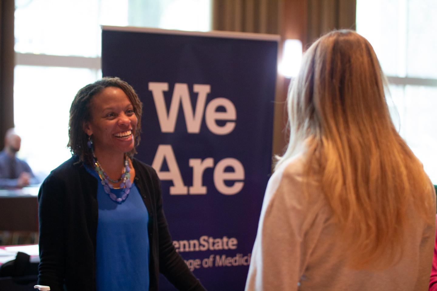 A student and recruiter at a recent expo talking in front of a Penn State "We Are" banner.