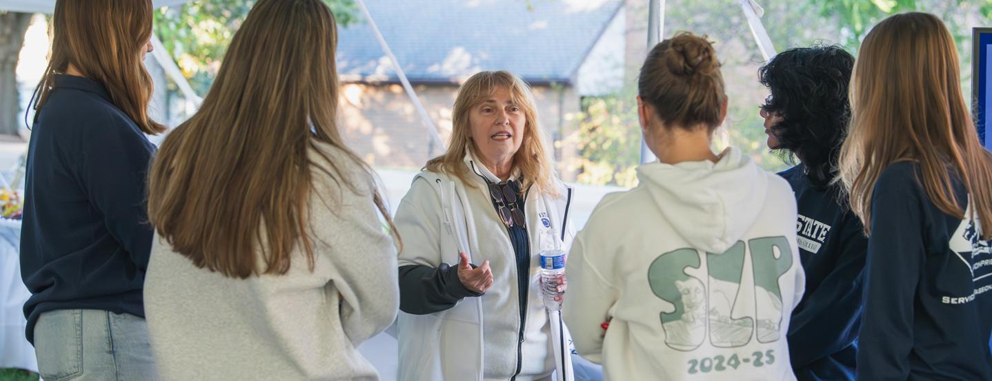 A group of students from the Science Lions Pride talk with a guest at the Fall 2025 Homecoming Tailgate.