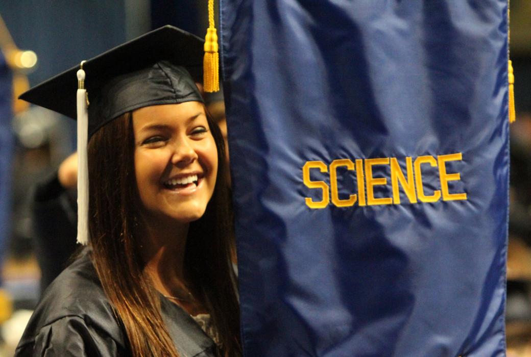A science major graduate standing with the "science" banner