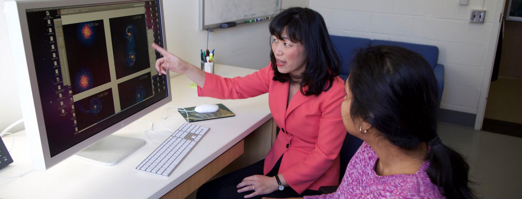 A faculty member gesturing to information on a computer screen.
