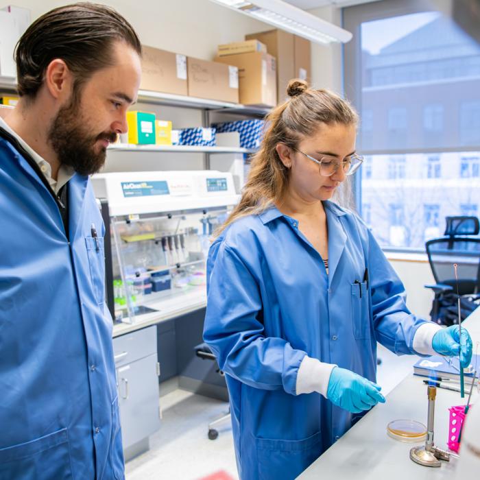 Jordan Bisanz working with a graduate student in his lab.