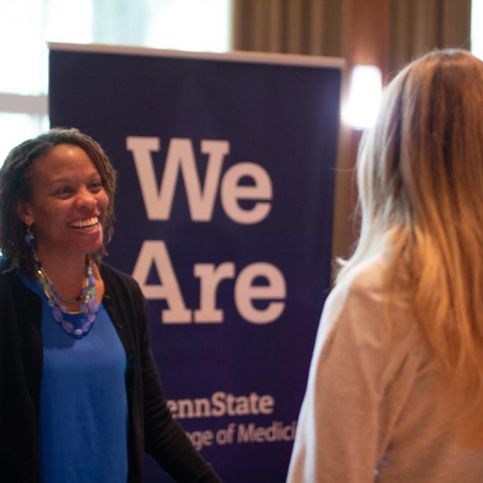 A student and recruiter at a recent expo talking in front of a Penn State "We Are" banner.