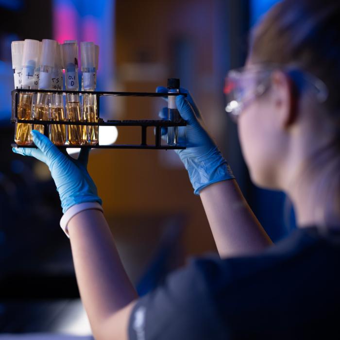 A student working in the lab holding up a case of viles as she check the labels on each vile.