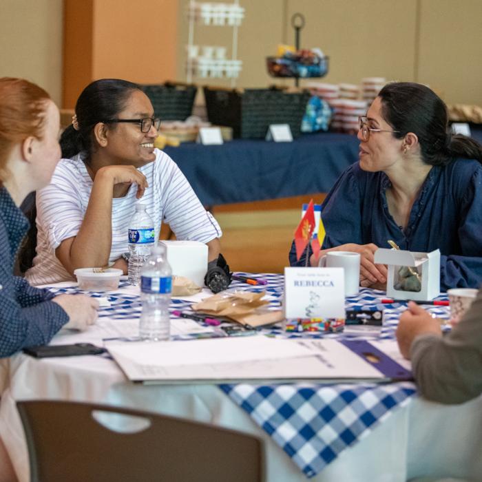 A group of four people sitting at a table and talking during the World Cafe event held at the HUB-Robeson Center