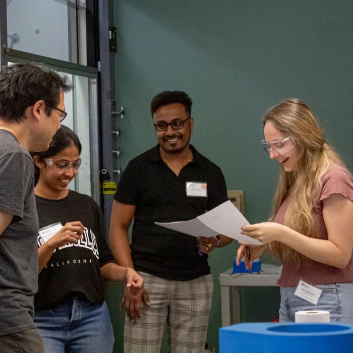 Students in the bioinorganic workshop talking in smiling as the work together on a project in the lab.