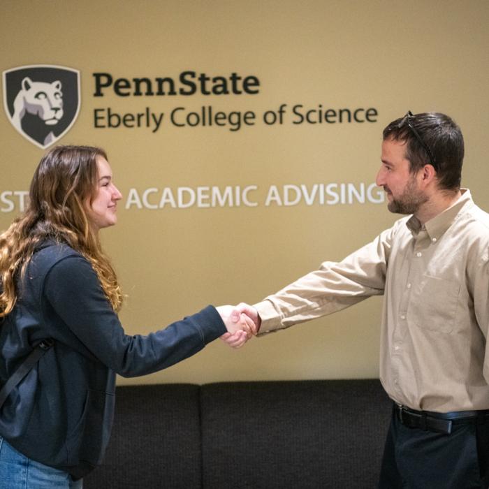 Photo of a biology adviser welcoming a student to the academic advising center in Ritenour Building.