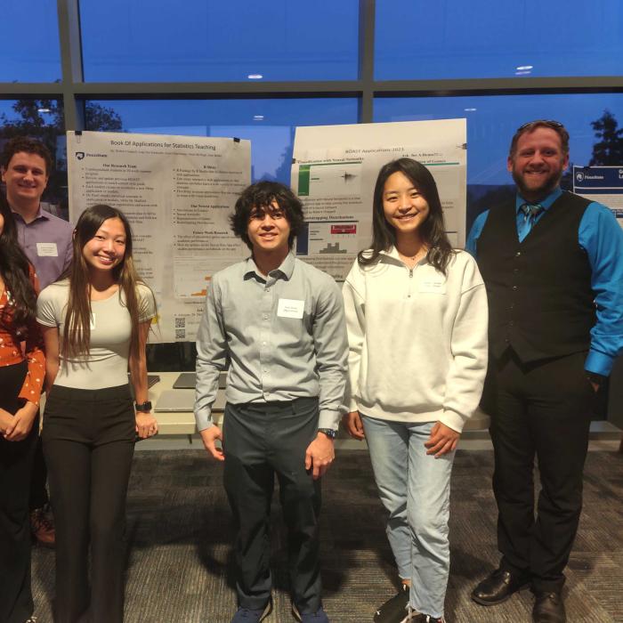 students and faculty stand in front of poster