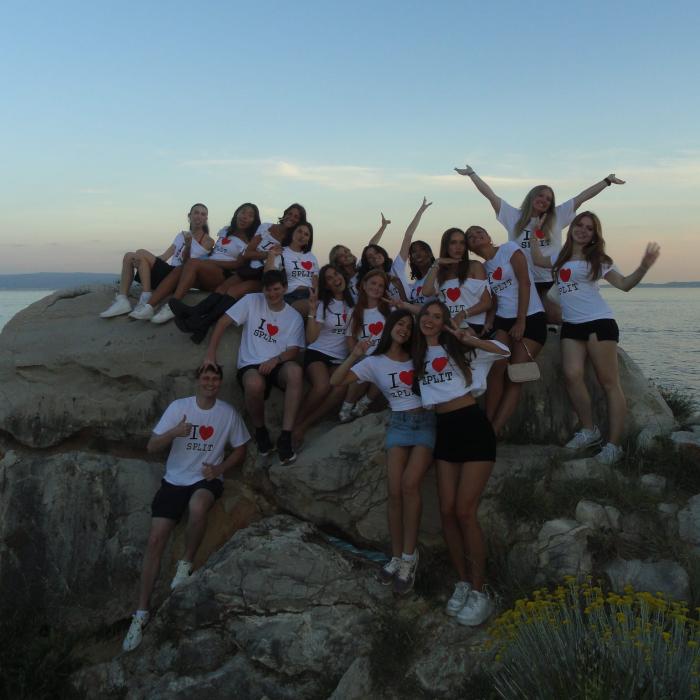 Students studying abroad Split, Croatia through the Biomedicine on the Adriatic program posing on a large rock in front of a bay.