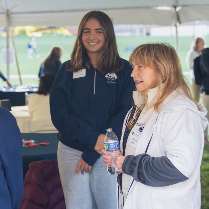 An alumna talking to students during the 2025 Homecoming Tailgate.