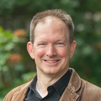 professional portrait of Derek Fox smiling, in front of blurred background