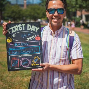 Randy McEntaffer holding a first day of school board.