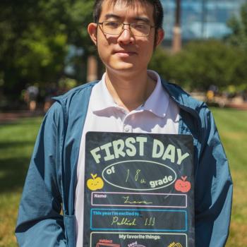 Physics student holding a first day of school board. 