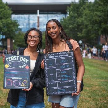 Two students holding first day of school boards.