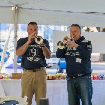 Two gentleman in blue Penn State gear playing trumpets at the Penn State Homecoming tailgate.