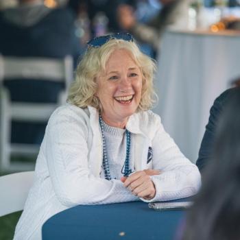 A woman smiling and laughing while sitting at the Penn State Homecoming tailgate.