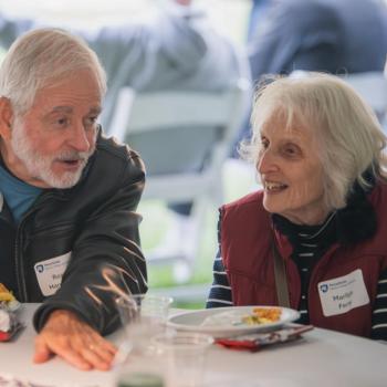 Two people talking at a table while attending the Penn State Homecoming tailgate. 