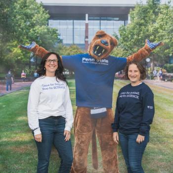 Kristen Robinson and Dean of the Eberly College of Science Tracy Langkilde posing in front of the backdrop of the Penn State Nittany Lion mascot wearing an Eberly College of Science shirt. Both Kristen and Tracy are wearing shirts that say Come for Football, Stay for Science.
