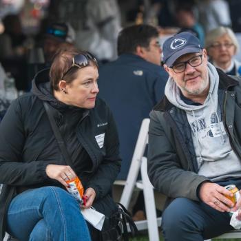 Two people at the Penn State Homecoming tailgate sitting and watching the parade.