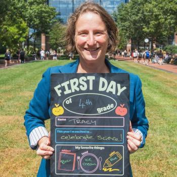 Dean Tracy Langkilde holding up a first day of school board.