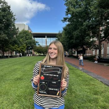 Student holding a first day of school chalkboard.