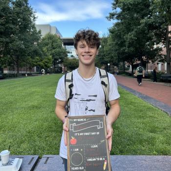 Student holding a first day of school chalkboard.