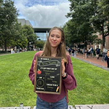 Student holding a first day of school chalkboard.