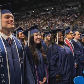 Students stand prior to move the tassels on their mortarboard.