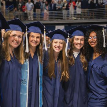 A group a coed students poses together and smiles for the camera.