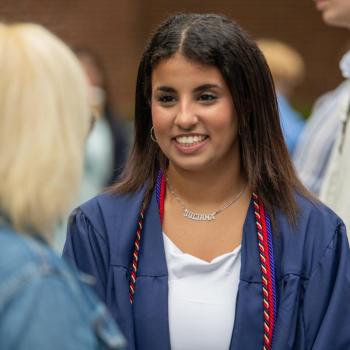 A coed smiles as she talks to guest during the commencement reception.