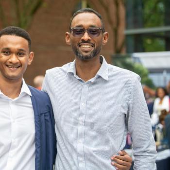 A student and a family member smile as they pose for a photo.