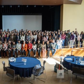 Large group photo of all event attendees gathered onstage.