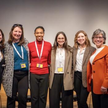 Group of panelists standing together onstage for a photo.