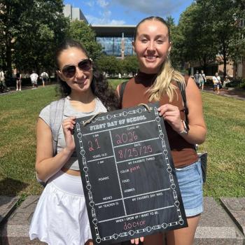 Two girls holding a first day of school board.