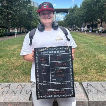 Student holding a first day of school board.