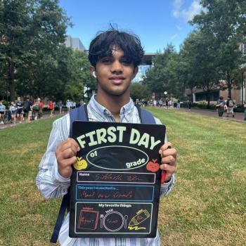 Student holding a first day of school board.