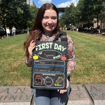 Female student holding a first day of school board.
