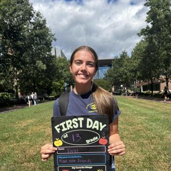 Student holding a first day of school board.