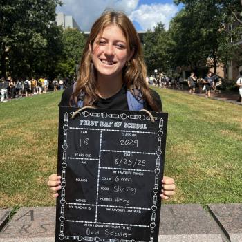Student holding a first day of school board.