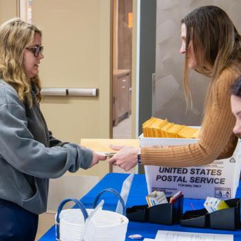 A coed at the graduation checkout event being hand an envelope by a staff member.
