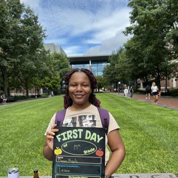 Student holding a first day of school chalkboard.