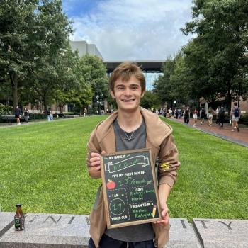 Student holding a first day of school chalkboard.