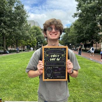 Student holding a first day of school chalkboard.
