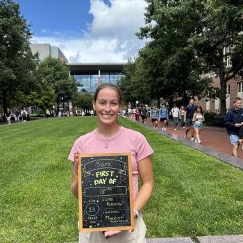 Student holding a first day of school chalkboard.