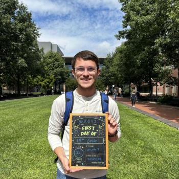 Student holding a first day of school chalkboard.