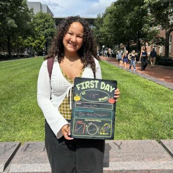 Student holding a first day of school chalkboard.