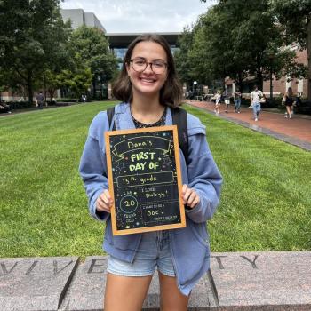 Student holding a first day of school chalkboard.