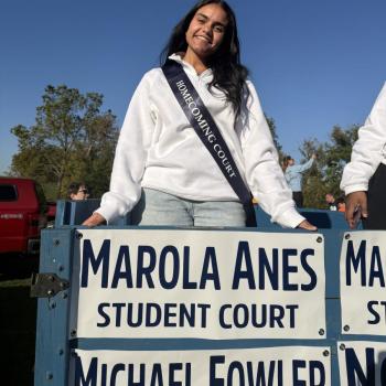 Marola Anes, Eberly representative of the Penn State Homecoming court, standing on the float above a sign that says Marola Anes Student Court.